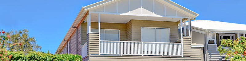 Top level front of a house, white aluminium vertical slat balustrade contains the balcony