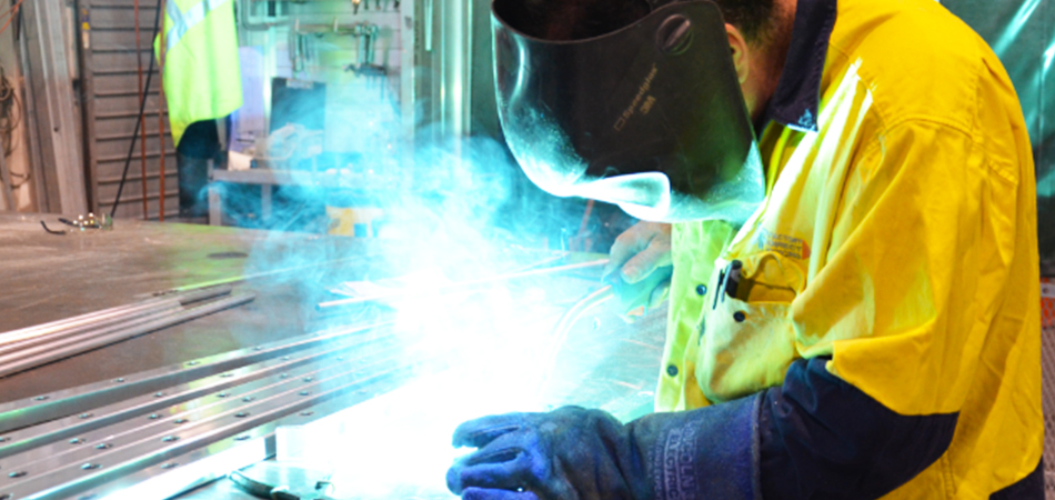 Welder wearing safety equipment, welding pieces of a gate together.