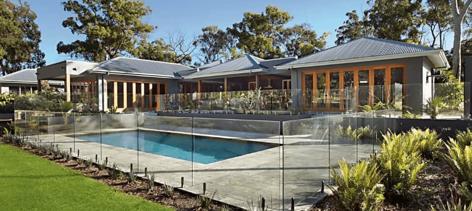 Modern house backyard with an in-ground pool, surrounded by Frameless glass pool fencing.