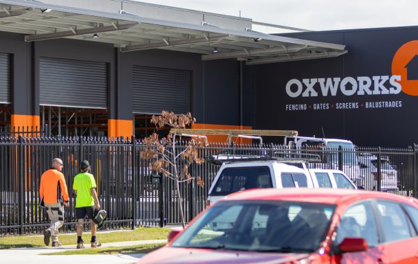Two tradesmen walking towards the entry gate of the Oxworks warehouse
