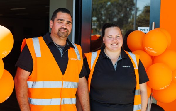 Two Oxworks employees smiling and standing in front of a decorated office entry